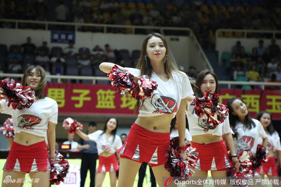 在绚丽的舞台灯光下，几位啦啦队员排成一列，动作整齐划一，她们修长的身姿和灿烂的笑容交织在一起，构成了一幅充满动感与美感的画面。