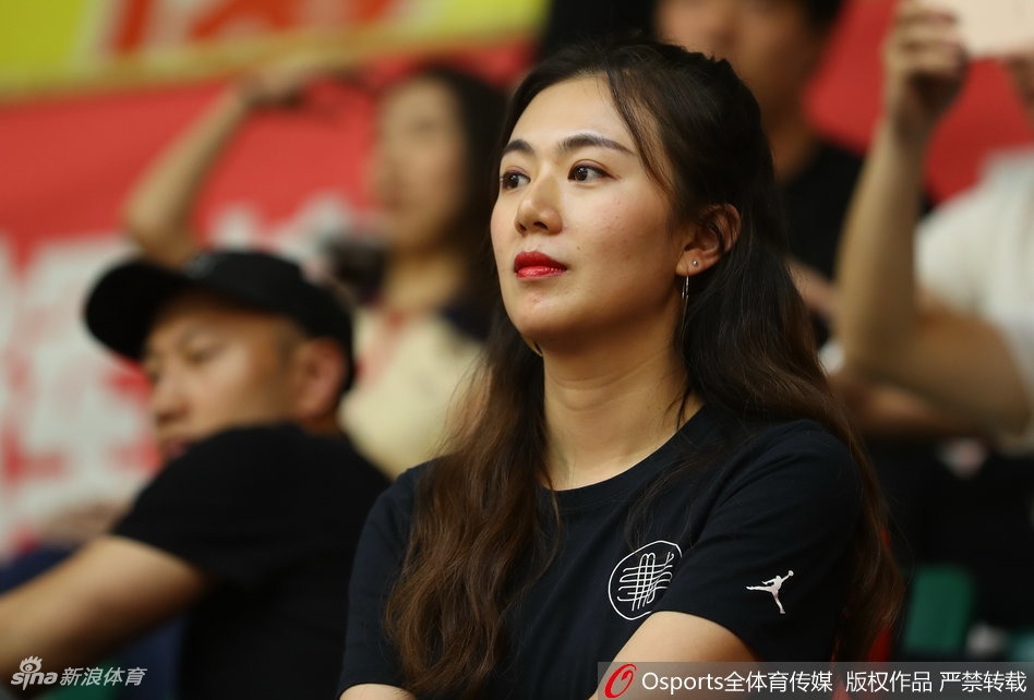 一对情侣球迷在看台上甜蜜互动，女孩头靠在男友肩上，脸上画着广厦队的队徽彩绘，笑容甜美幸福