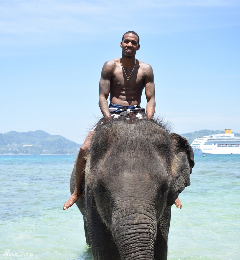 亚当斯在一处具有异域风情的建筑前驻足,他侧身对着镜头,背景是温暖的阳光和独特的建筑轮廓,整个画面呈现出一种悠然自得的度假氛围。