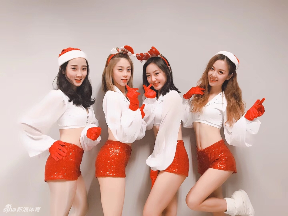 甜心宝贝头戴毛绒圣诞帽，对着镜头俏皮眨眼，手中金色的花球与红色装扮相映成趣，洋溢着满满的节日元气。