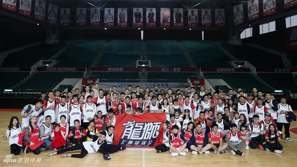 训练间隙,一名广州男篮球员弯下腰为蹲在地上的小球迷在篮球上签名,周围站满了其他等待签名的热情球迷,场面十分有爱。