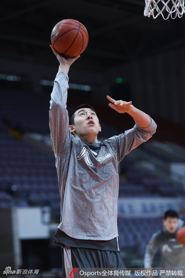 丁伟指导侧身靠近阿的江，手指向场内，似乎在分享一个重要的战术观察，两人身后的球员正在紧张热身。