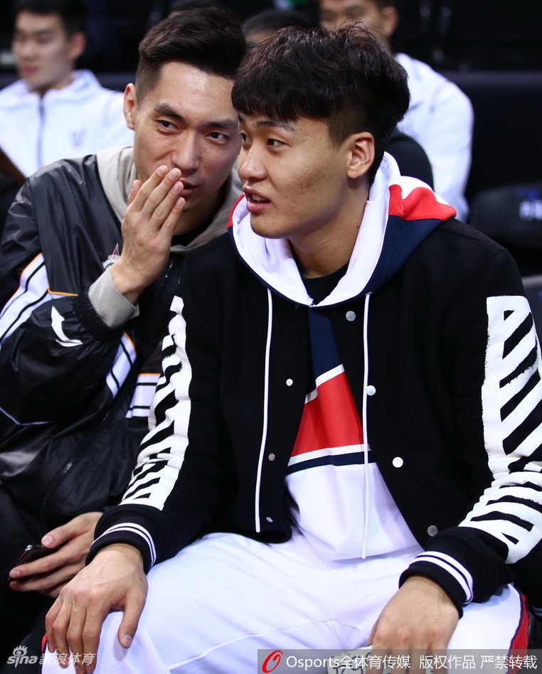 辽宁队中锋韩德君在看台上露出标志性的憨厚笑容，双手似乎正在为场上星锐球员的一次精彩配合鼓掌叫好。