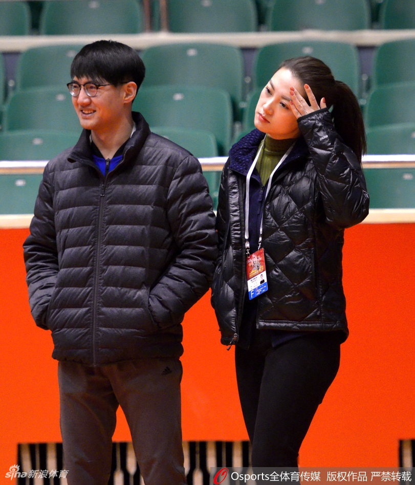在训练结束后的场边,美女记者将话筒递向一位浑身湿透的新疆队主力球员,两人面带微笑进行着赛后简短的交流,背景是空旷的看台和整理器材的助理教练,氛围轻松而专业。