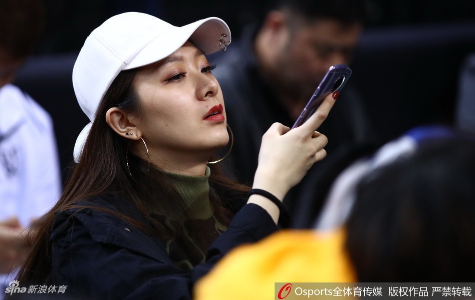 翟晓川与妻子杨思雨坐在CBA全明星赛场边,两人都穿着深色系休闲装,神情专注地看着场内激烈的星锐赛,偶尔低声交流,眼神中满是默契与温情。