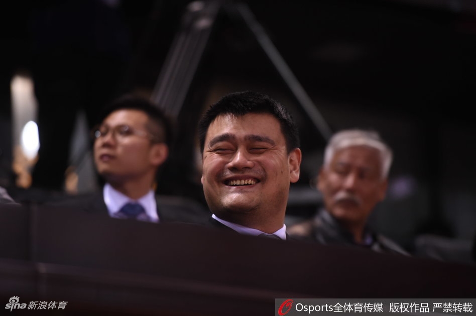 姚明双手抱在胸前，脸上挂着无奈又好笑的表情，眼睛睁得圆圆的，似乎在为场上球员投出的离谱三线球感到不可思议。