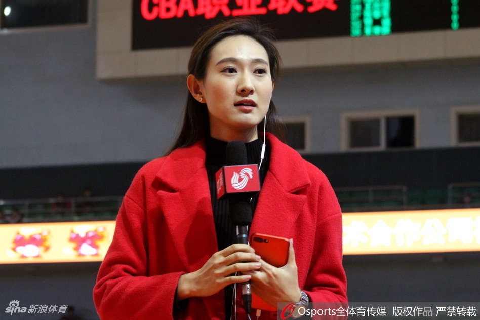 冬日的济南奥体中心外场,一位身着白色长款羽绒服的美女记者正在寒风中整理采访提纲,她回眸的瞬间,眼神中充满了对即将开始比赛的期待与专注,哈出的热气在空气中化作一团白雾。
