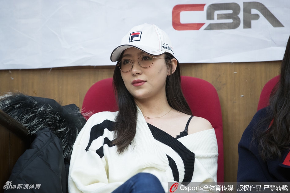 看台上的另一角，广厦的铁杆球迷们挥舞着旗帜，声嘶力竭地为球队呐喊。旗帜上猛狮的标志栩栩如生，与看台上那位恬静的美女形成鲜明对比，一静一动，共同构成了广厦主场最真实的球迷文化。