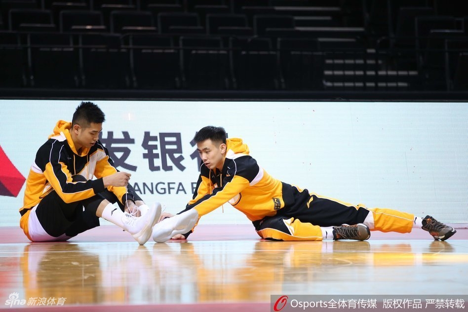 队友在练习运球，郭艾伦却像个顽皮的孩子一样突然从背后伸出双手试图掏球，恶作剧得逞后脸上立刻绽放出灿烂又得意的笑容。