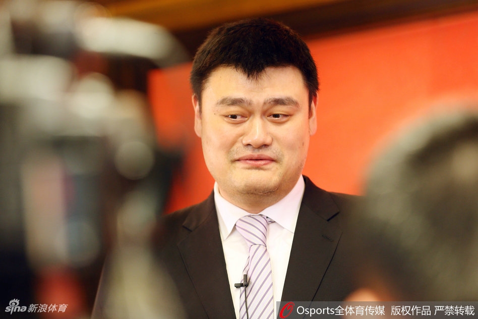 姚明在汉秀剧场内微微低头认真倾听工作人员讲解，标志性的11号球衣虽已退役，但他举手投足间依然是赛场上那个令对手敬畏的小巨人。