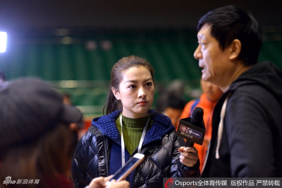 全景镜头下,山东男篮的队员们正在进行快攻上篮练习,篮球在空中划出弧线。美女记者站在场边的摄影位,与身后巨大的球队标志相映成趣,展现出职业体育报道的规范与热情。