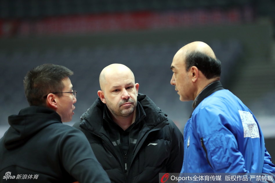 王治郅弯下腰，用手指点着地板上的位置，向年轻的内线球员讲解跑位和卡位的要领。他认真的侧脸，像是一位严师在为弟子们绘制通往胜利的地图。