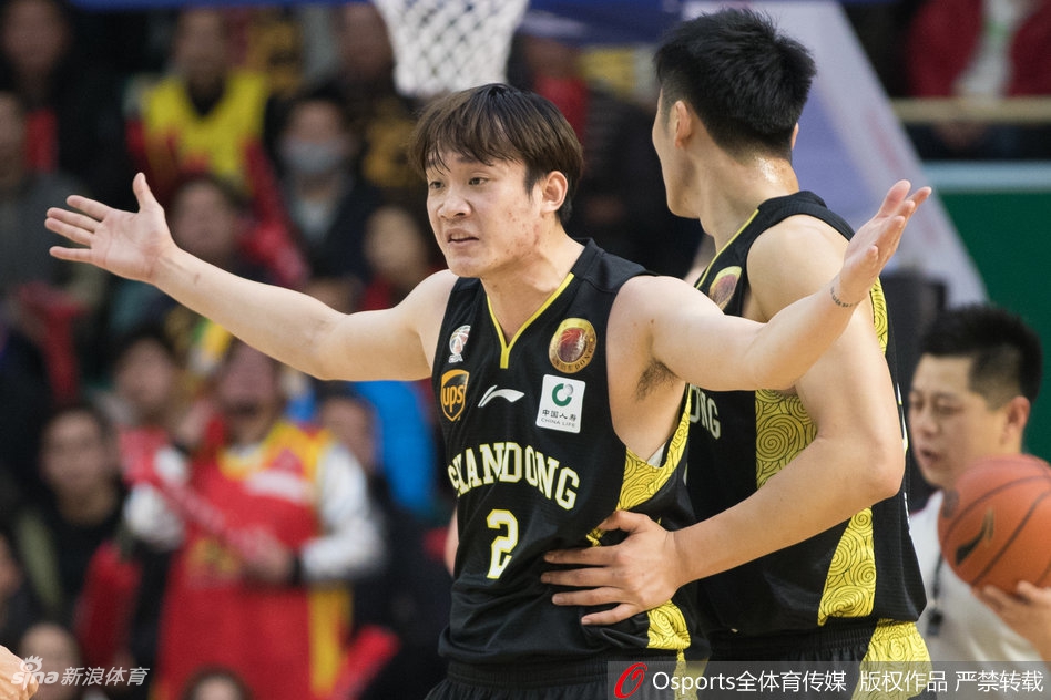 丁彦雨航在对手严防下依然自信出手，篮球在空中划出优美弧线，场边的灯光和观众席虚化背景，定格了这一瞬间的专注与决心