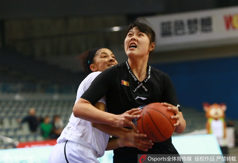 广东队球员沈怡面对贴身紧防，冷静地寻找传球路线，她灵动的身影与新疆队员的严密防守形成鲜明对比，仿佛在刀尖上跳舞。