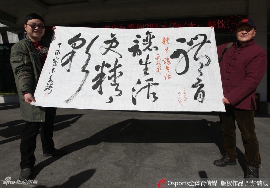 热情的球迷们紧紧跟随缓缓启动的大巴车，他们挥舞着手中的旗帜，用整齐划一的口号为心中的英雄送上最后一段路的陪伴。