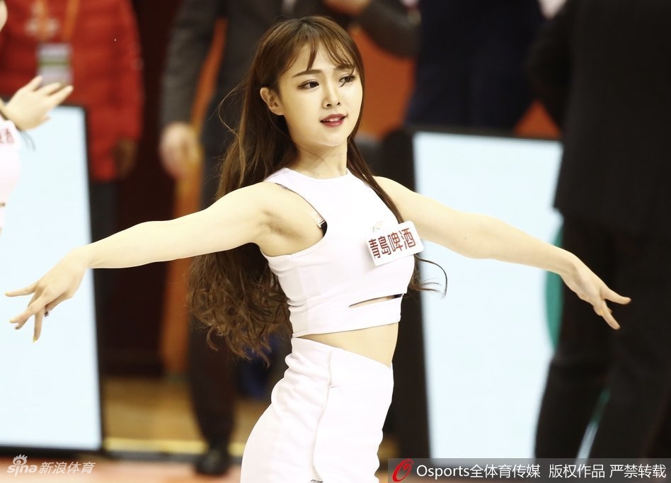 身着校园风短裙的啦啦队女孩，在体育馆看台上回眸一笑，眼神清澈动人