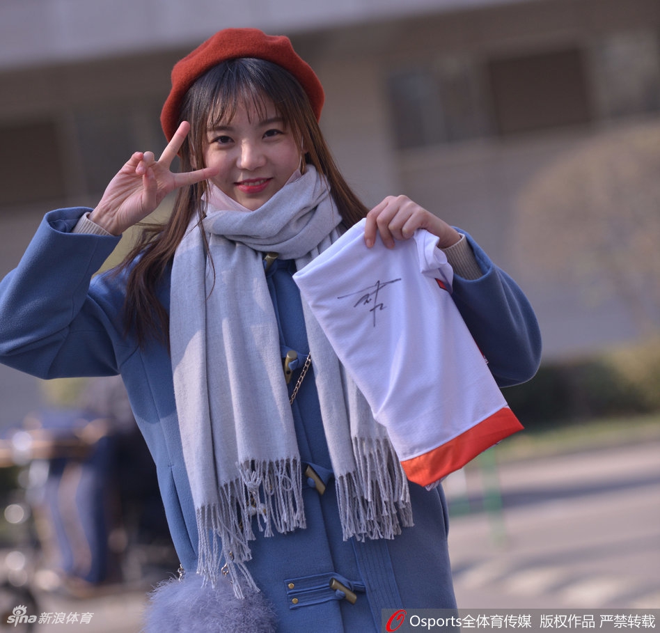 温柔一笑的女球迷,在喧嚣的赛场中显得格外宁静美好,她身着休闲外套,是时尚与体育的完美结合。