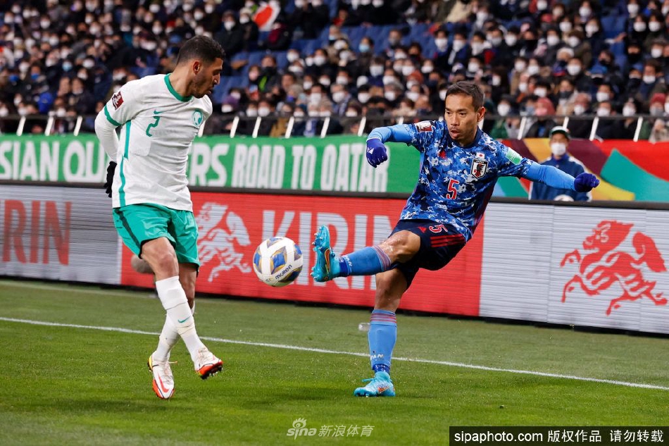 长友佑都高举双手庆祝胜利或向球迷致意，身后是模糊的绿茵场与看台，画面充满动感与激情