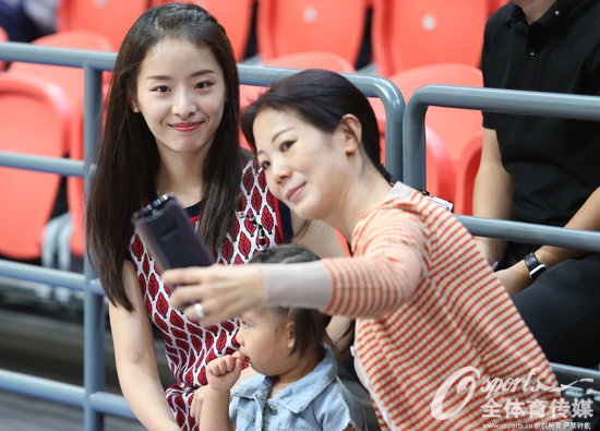 孙桐林抱着女儿在场边，他用宽厚的手掌小心翼翼地托着孩子，女儿则乖巧地依偎在爸爸胸前，巨大的身材反差萌感十足。