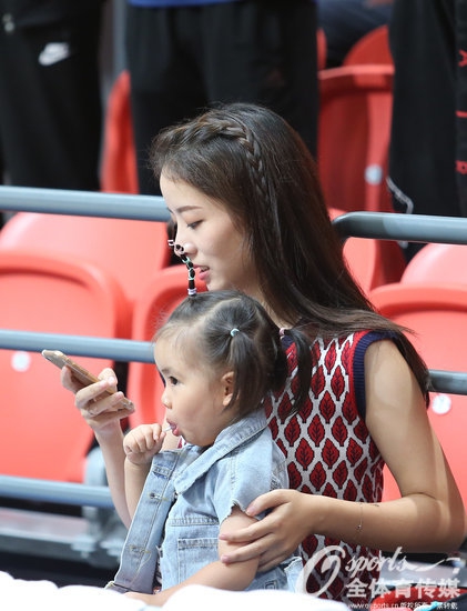 镜头拉近，孙桐林的女儿睁着圆溜溜的大眼睛好奇地打量着周围的一切，肉嘟嘟的小脸蛋和浓密的头发让她成为全场最可爱的场边‘吉祥物’。