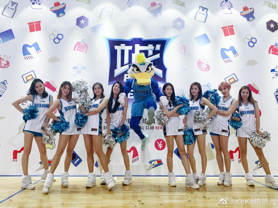 训练场上，巅峰啦啦队的队员们身着红白相间的活力队服，整齐划一地排开。她们高扎马尾，笑容灿烂，修长的身形在光影下宛如模特阵容，尽显青春朝气。