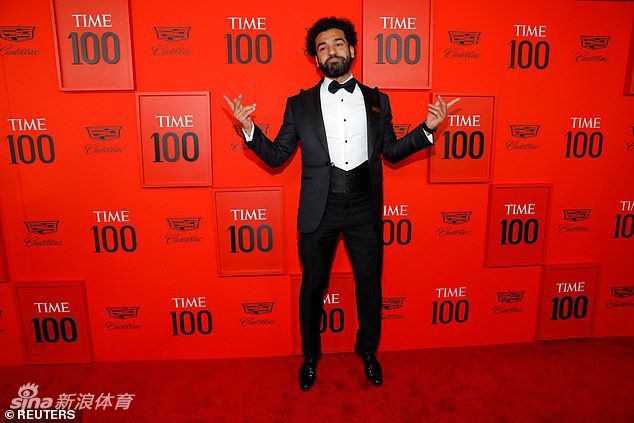 在纽约林肯中心的典礼红毯上，萨拉赫身着笔挺的深蓝色西装，内搭白色衬衫，脸上带着标志性的温和微笑，右手轻放在胸前，仿佛正感受着这份来自场外的荣耀与心跳。聚光灯下，他不再是球场上风驰电掣的猎豹，而是一位从容自信、引领时代的绅士。