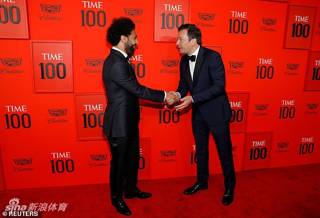 盛典内场，萨拉赫手持印有自己名字和肖像的《时代》杂志特刊，与身旁的两位同样入选的嘉宾轻松交谈。他微微侧身，专注地倾听，脸上洋溢着谦逊而友好的笑容，手中的杂志封面在闪光灯下格外醒目，仿佛在无声地讲述着这一年他用双脚书写在绿茵场上的传奇故事。