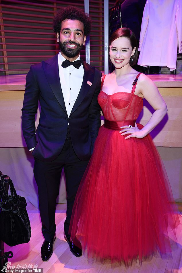 这张近景特写中，萨拉赫站在背景板前，目光深邃地凝视着远方。西装革履的他身姿挺拔，胸前的口袋巾点缀得恰到好处，背景板上巨大的‘TIME 100’字样若隐若现。这一刻，光影在他棱角分明的脸庞上刻画出坚毅的轮廓，仿佛一尊承载着梦想与希望的现代雕塑。