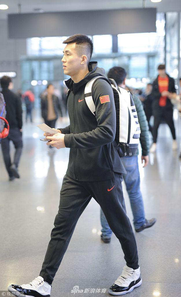 身穿白色外套的后卫胡明轩在人群中显得格外青涩，他推着行李车，目光清澈而坚定，作为广东队年轻一代的代表，他将在国家队开启新的篇章。