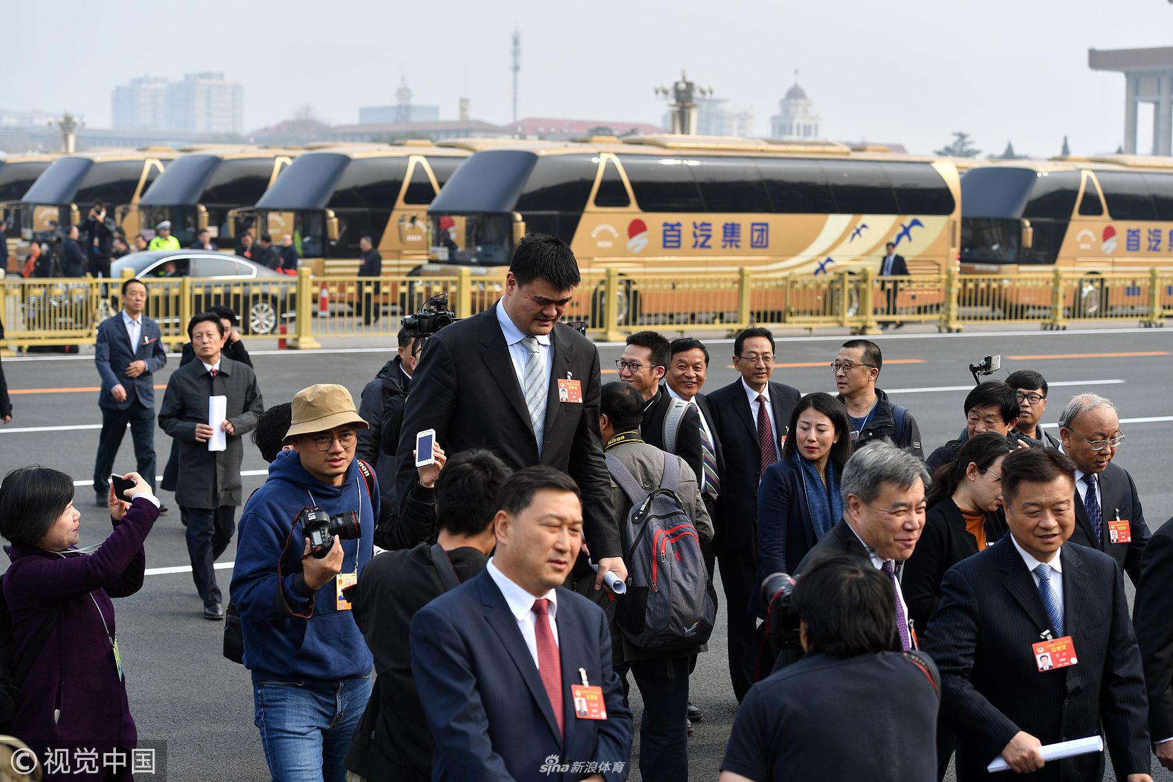 姚明在政协会议间隙与另一位体育界委员王艳霞交谈，两人面带微笑，姚明侧身低头倾听，展现出体育人之间相互支持、共谋发展的融洽氛围。