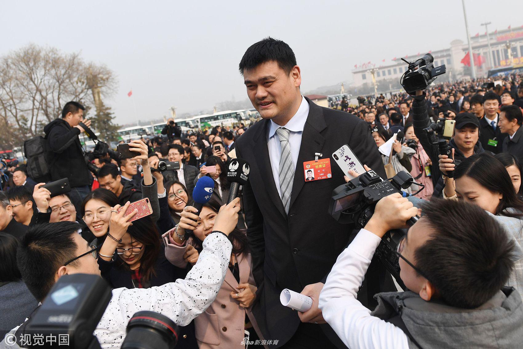 身着深色正装的姚明与其他委员并肩走向人民大会堂，他神情专注而从容，步伐坚定，仿佛正从体育赛场走向为国履职的新舞台。