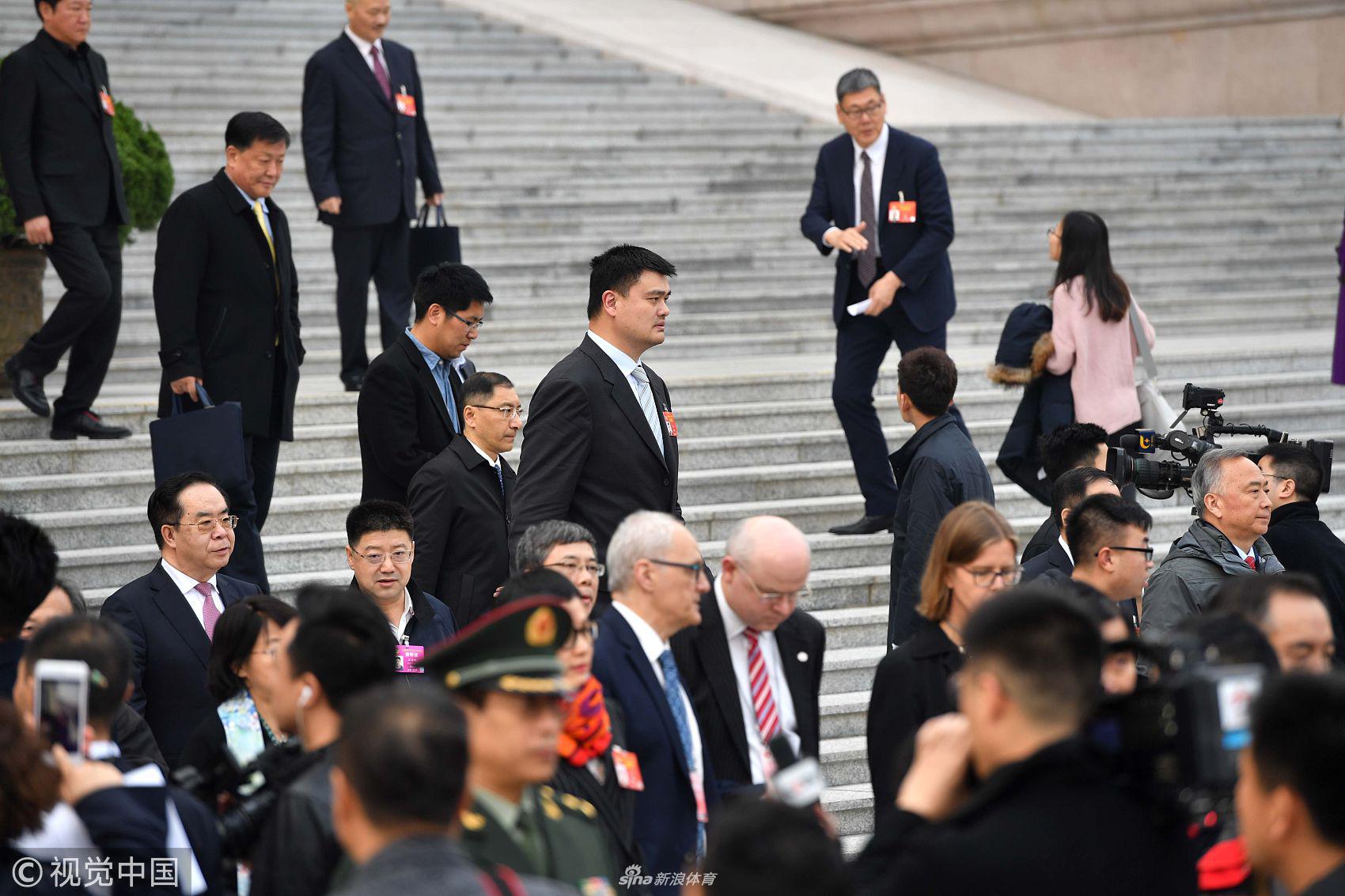 姚明走出会议室，一边看着手机一边与工作人员交流，在会场走廊的灯光下，他高大的身影投在地毯上，忙碌而有序的履职日常在此刻定格。