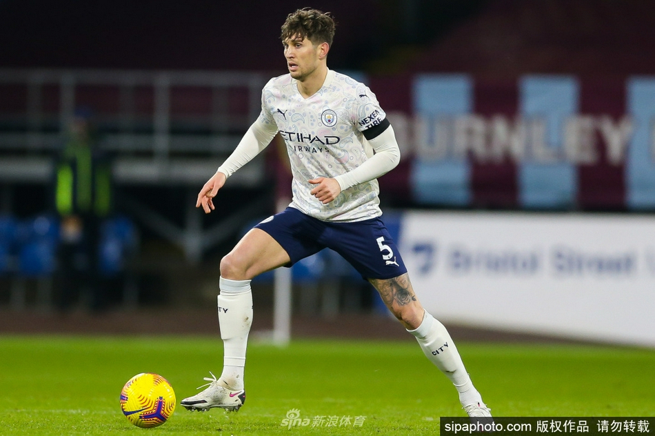 斯通斯在续约成功后，于伊蒂哈德球场留下珍贵影像。他身着标志性的曼城天蓝色战袍，眉眼间流露出对未来的笃定与喜悦，背景中若隐若现的冠军锦旗见证着他与俱乐部的共同成长。