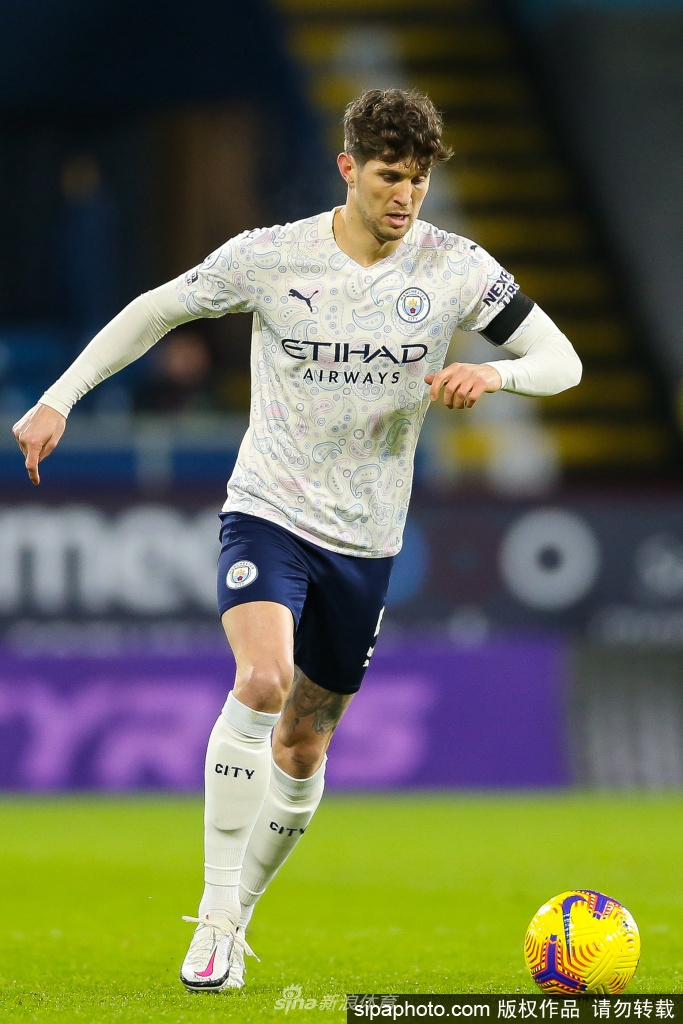 斯通斯身披曼城战袍，在比赛入场通道中留下帅气身影。明亮的灯光为他勾勒出金色的轮廓，他神情专注而放松，仿佛一位即将踏上战场的优雅骑士。胸前闪耀的俱乐部徽章，不仅代表着荣誉，更承载着未来五年继续捍卫蓝月荣耀的承诺。