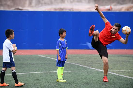 这是马丁内斯（右一）指导孩子们练习足球。新华社记者杨文斌摄