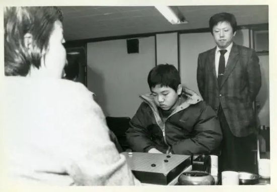 李在龙站在对局中的少年李昌镐身后观战。这是一张满溢着亲情力量,极富象征意义的历史照片。