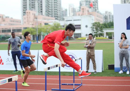 图说：曾建航为小选手示范跨栏动作。