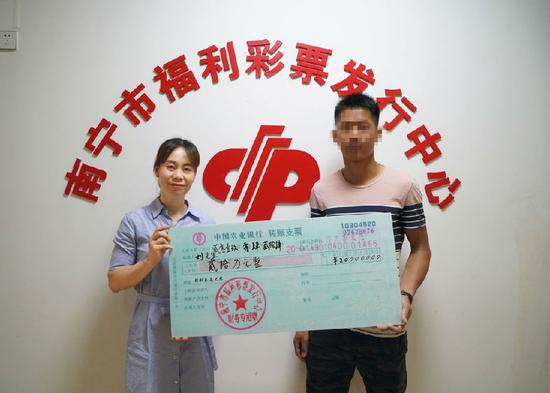 图为:南宁市福彩中心工作人员为刘先生颁奖