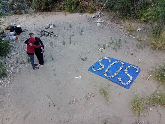一家人用石头在地面上拼出了“SOS”字样