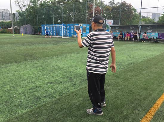 家长在场边给孩子摄像。“足球本”