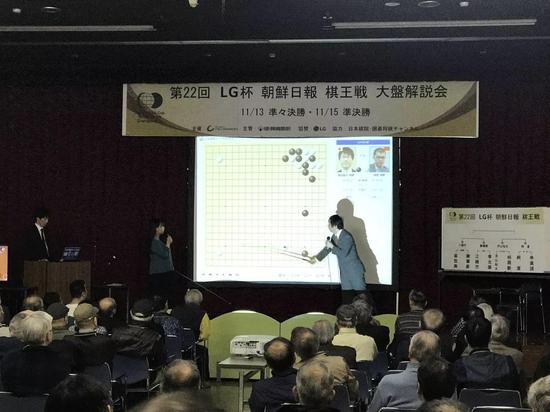 王铭琬九段和奥田彩三段担任大盘讲解,负责在大屏幕落子的是富士田明彦六段(图片摘自日本棋院)