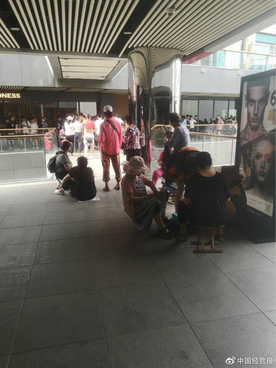 6月15日上午,北京三里屯Madness门店外,聚在一起打牌的中年人。