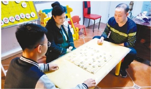 蘭先賀和小兒子蘭程在家中對弈,王永芹在旁邊觀看