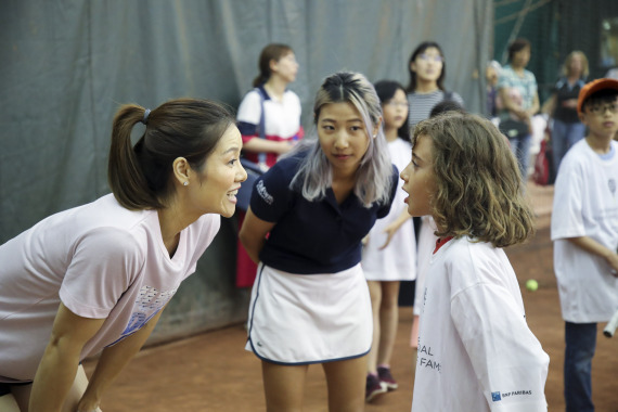 7月18日，李娜（左）在曼哈顿的萨顿东网球俱乐部与学习网球的青少年交流。新华社记者王迎摄