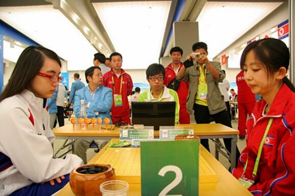 ▲ 2010年亚运会,中国台湾棋手黑嘉嘉与朝鲜棋手赵新星在对局。当时,朝鲜队的教练是李凤日。
