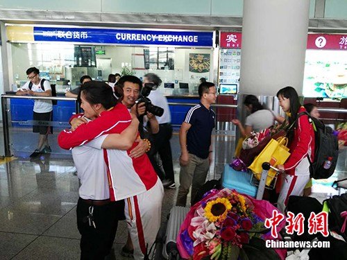 中国女子重剑队队员和前来接机的领队王健拥抱。中新网记者 宋宇晟 摄