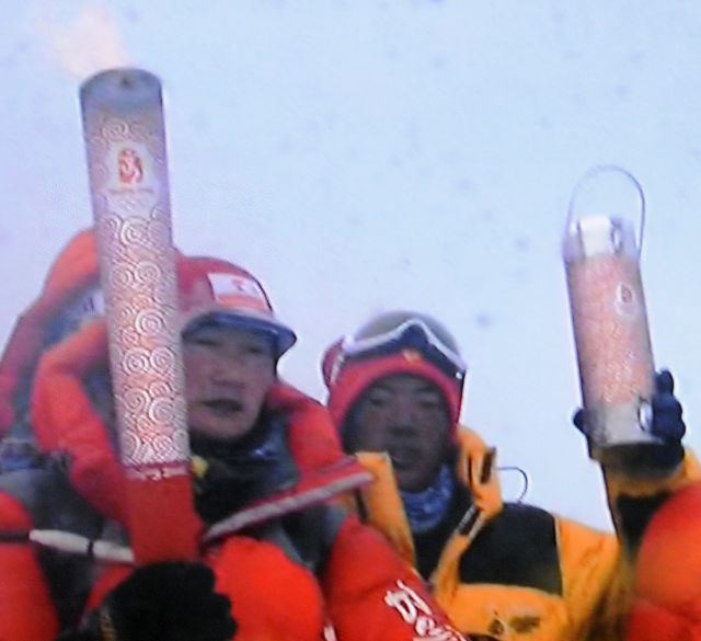 图为2008年5月8日，北京奥运圣火珠峰传递登山队成功登顶珠峰。这是第五棒、也是最后一棒火炬手次仁旺姆（左）在珠峰顶峰展示手中的“祥云”火炬（电视画面）。