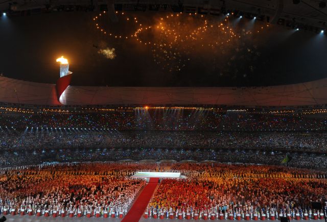 图为2008年8月8日，第29届北京奥运会开幕式在国家体育场隆重举行。这是主火炬在国家体育场内燃烧，场外礼花绽放。新华社记者赵鹏摄