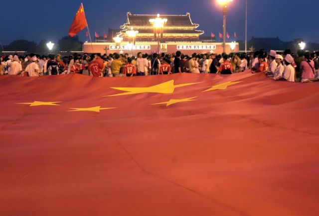 图为2001年7月13日，2008年奥运会举办城市投票揭晓，北京赢啦！这是在天安门广场庆祝胜利的人群展开一面巨型五星红旗。新华社记者李勇摄