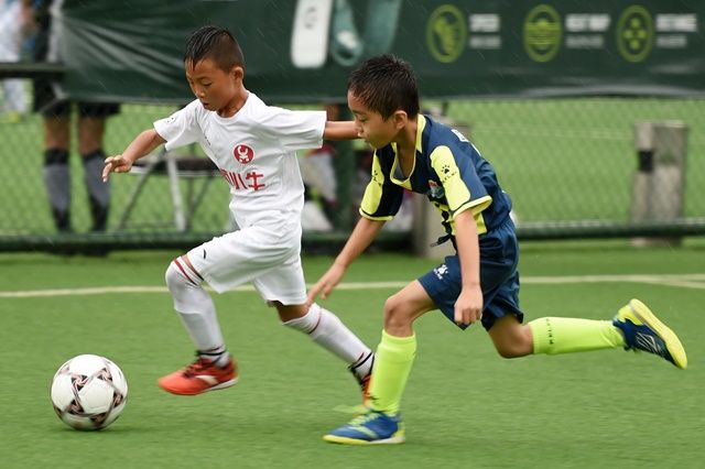 两名参加“百队杯”8岁混合组决赛的小球员在比赛中。 新华社记者鞠焕宗摄